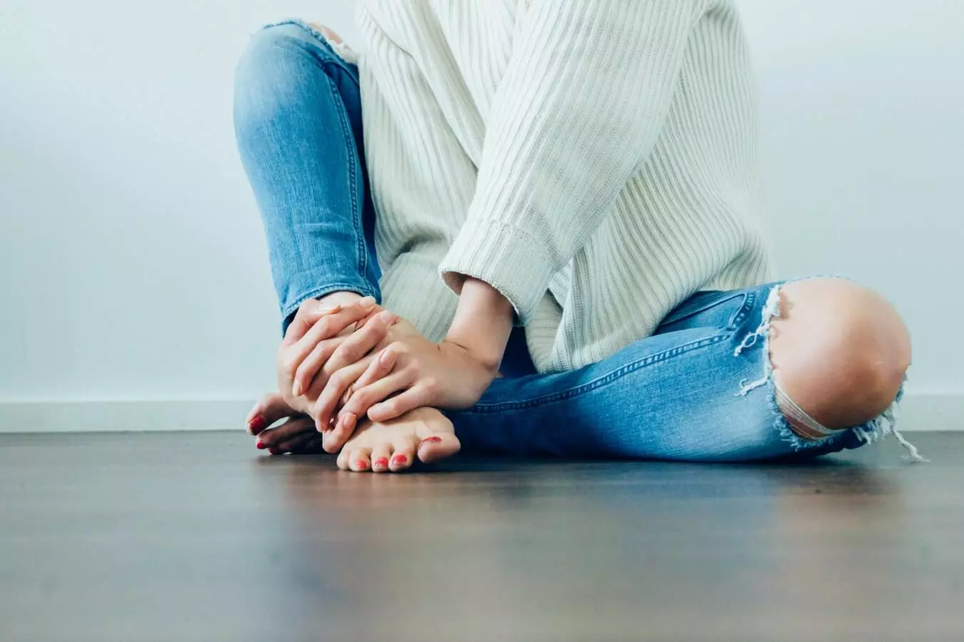 Mujer tocandose los pies reflexologia podal escuela quiros
